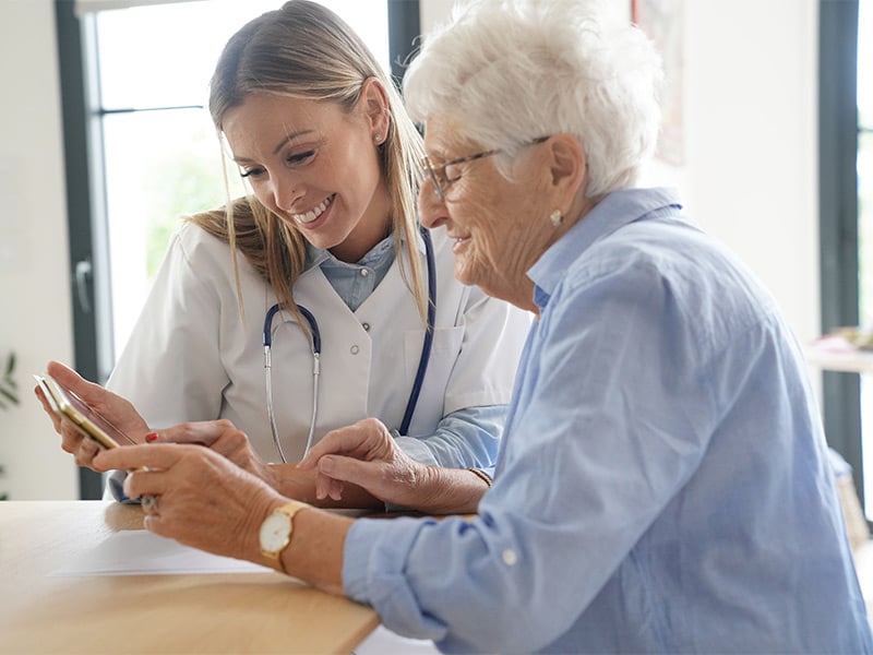 Elderly-woman-with-nurse-at-home-looking-at-tablet
