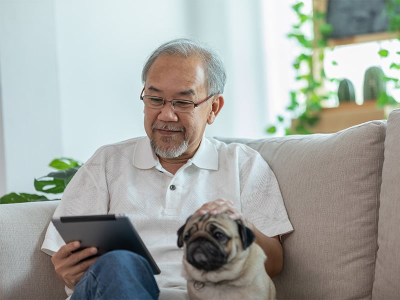 Happiness-elderly-asian-man-sitting-on-sofa-and-using-computer-tablet