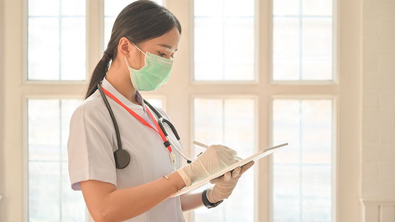 Nurse-wearing-gloves-using-tablet-to-record-covid-19-virus-infected-person